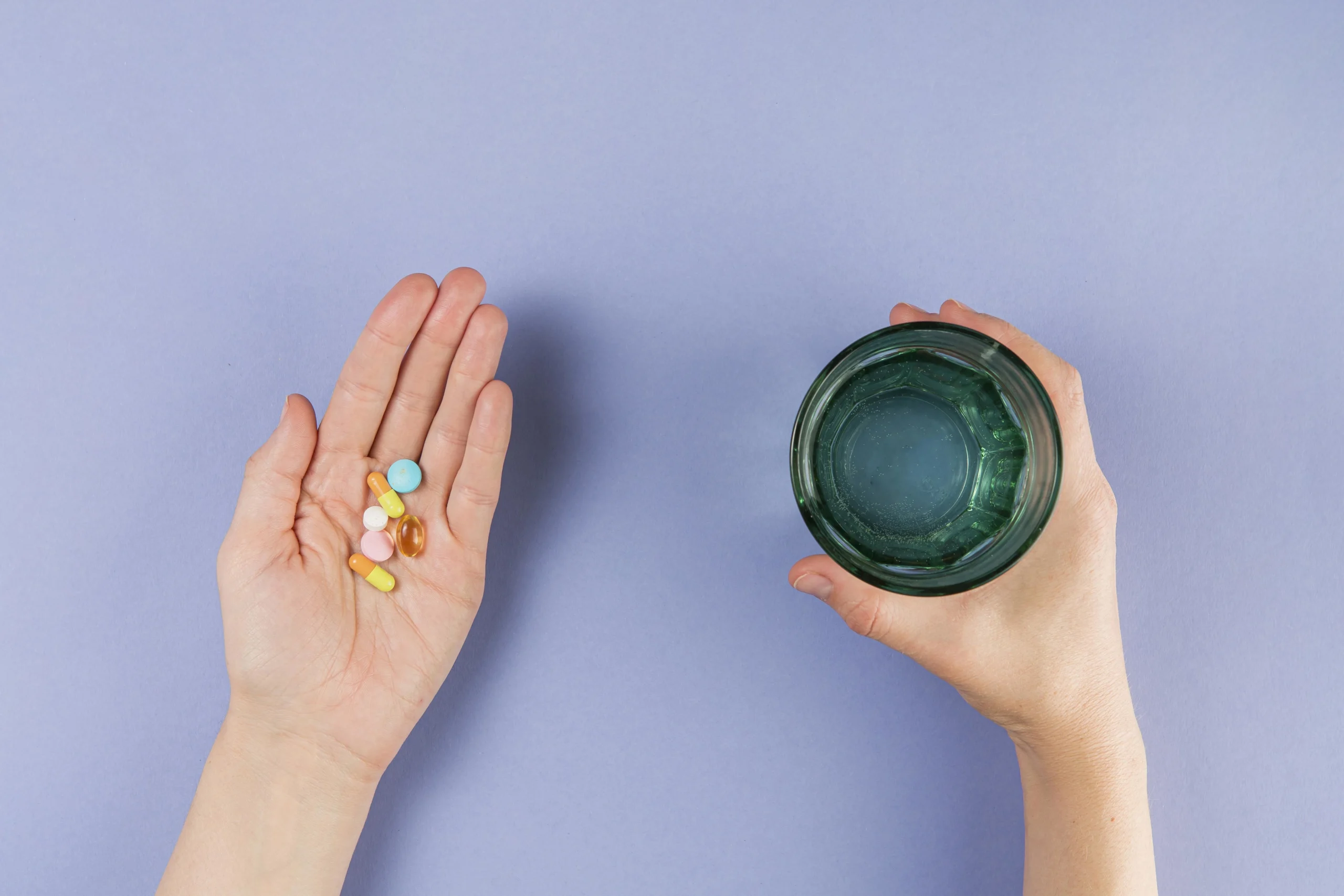 Hand mit Glas Wasser und Nahrungsergänzungsmitteln als Bild für Shopify Funktionen im Supplement-Shop