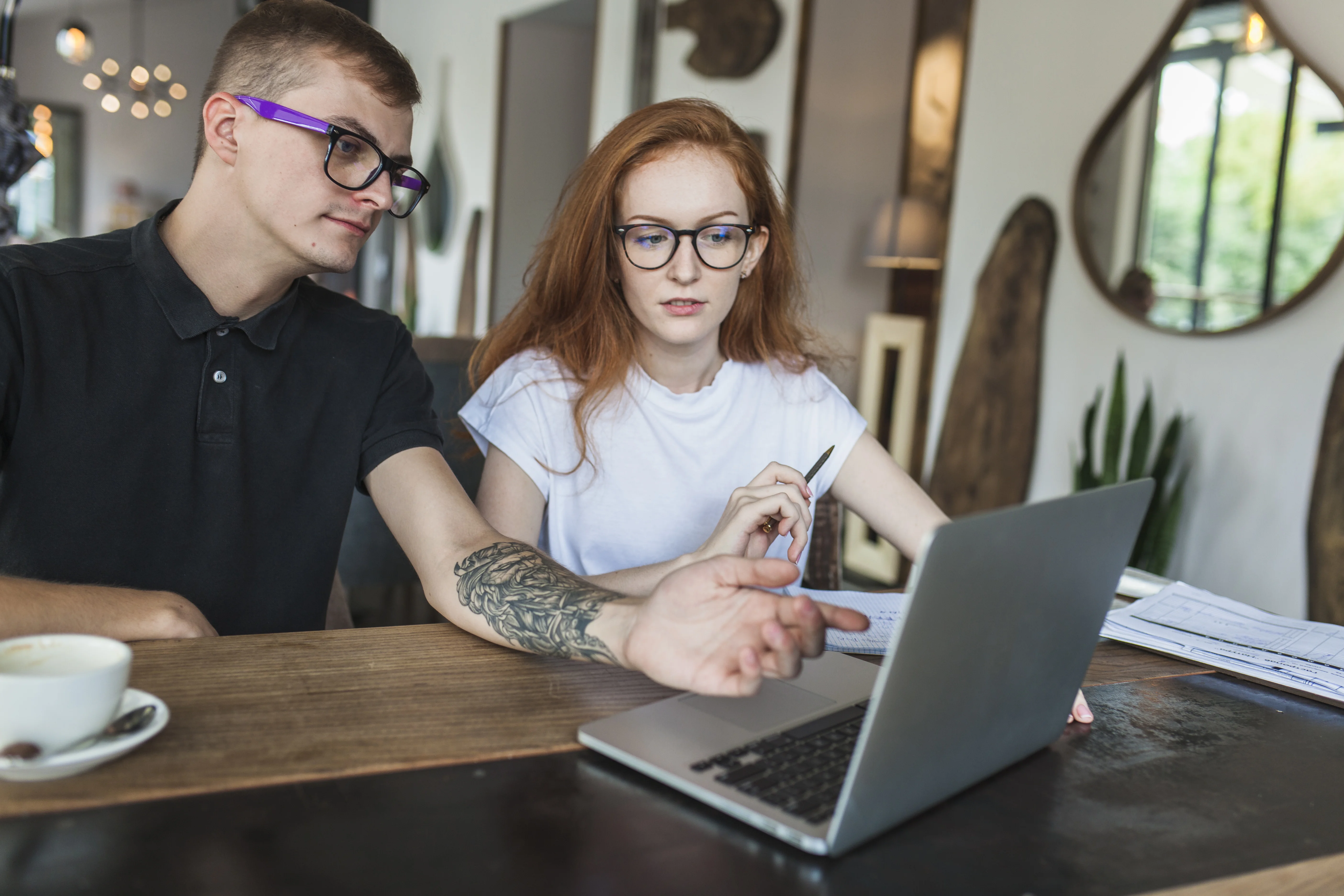 Two colleagues reviewing a Shopify blog post on a laptop, discussing where to place product links that turn readers into buyers