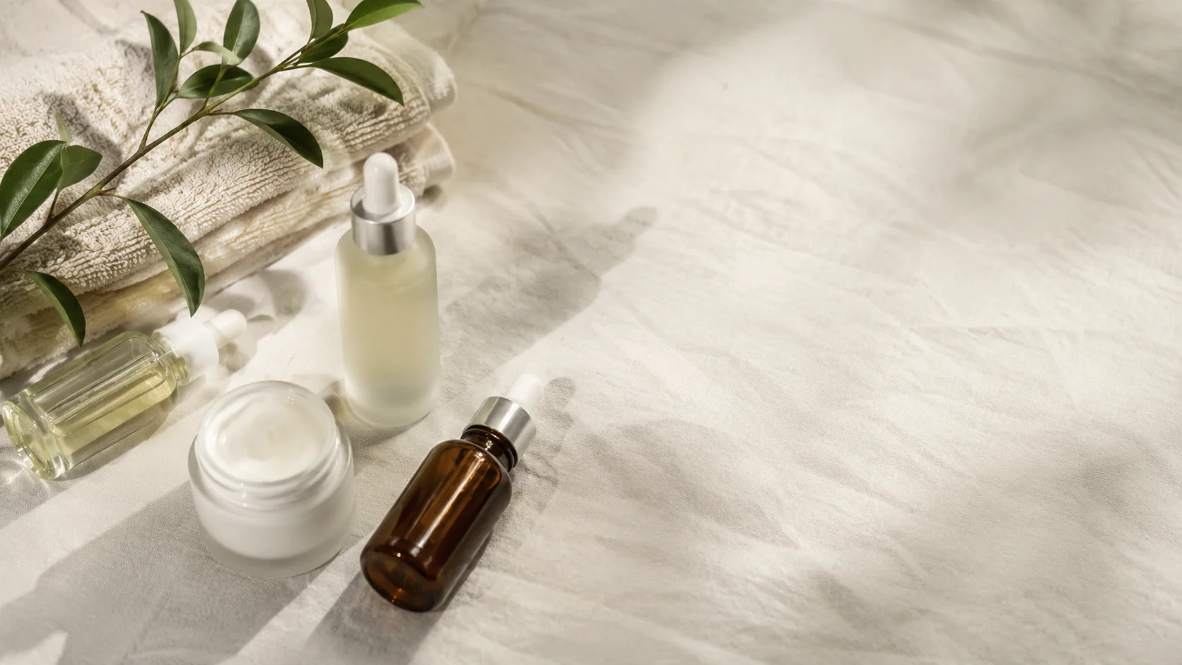 Minimalist skincare bottles and jars arranged on a neutral surface in soft daylight in Shopify